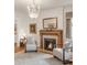 A cozy room featuring a fireplace, chandelier, and neutral armchairs with decorative pillows at 506 N Marion St, Denver, CO 80218