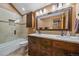 Bathroom featuring a double vanity with wood cabinets, a large mirror, and tiled shower at 6080 Kilimanjaro Dr, Evergreen, CO 80439