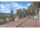 This deck features wood floors, a metal railing, and scenic views of the surrounding nature at 6080 Kilimanjaro Dr, Evergreen, CO 80439