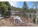 Multi-story home with decks nestled in a wooded area, featuring a bridge leading to the property at 6080 Kilimanjaro Dr, Evergreen, CO 80439