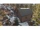 Charming brown cabin-style home nestled on a snowy hillside with a cozy balcony and mature trees at 6080 Kilimanjaro Dr, Evergreen, CO 80439