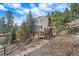 Exterior view of a home with a deck and hot tub surrounded by lush trees and stone steps at 6080 Kilimanjaro Dr, Evergreen, CO 80439
