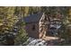 Brown garage surrounded by woods on a snowy day, offering both functionality and seclusion at 6080 Kilimanjaro Dr, Evergreen, CO 80439