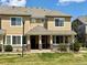 Inviting tan two-story townhome featuring a covered porch with brick accents and manicured landscaping at 16062 E Geddes Dr # 150, Aurora, CO 80016