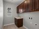 Practical laundry room featuring dark cabinets, tile floors, sink, and natural light from the window at 6877 Northstar Ct, Castle Rock, CO 80108
