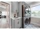 Modern laundry room with gray cabinets, patterned tile floor, sink, and stacked washer/dryer at 11702 Perry St, Westminster, CO 80031