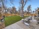 Backyard with plush green grass, mature trees, patio, and wooden privacy fence at 1140 S Elm St, Denver, CO 80246