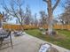 Backyard with plush green grass, mature trees, patio, and wooden privacy fence at 1140 S Elm St, Denver, CO 80246