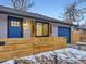 Close-up of a home's entrance featuring a blue front door, wooden privacy fence and garage door, and charming exterior lighting at 1140 S Elm St, Denver, CO 80246