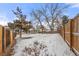 Spacious, snow-covered backyard, surrounded by a wooden fence and mature trees, ensuring privacy at 2023 S Idalia St, Aurora, CO 80013