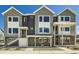 Modern townhomes with gray siding, brick accents, and white trim under a bright blue sky at 647 Skyhook St, Erie, CO 80516