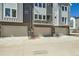 Street view of modern townhomes, showcasing individual garages, neutral paint, and contemporary design at 647 Skyhook St, Erie, CO 80516