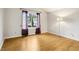 Light-filled bedroom with wood floors, a large window with sheer curtains, and a floor lamp at 17943 E Bates Ave, Aurora, CO 80013