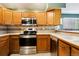 Charming kitchen featuring wooden cabinets, stainless steel appliances, and a window overlooking the outdoors at 17943 E Bates Ave, Aurora, CO 80013
