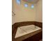 The large soaking tub features tile surround, inset windows, and warm lighting at 1688 Aquamarine Dr, Brighton, CO 80603