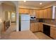 Galley-style kitchen adjoining hallway, with white refrigerator and wood cabinets at 1688 Aquamarine Dr, Brighton, CO 80603