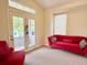 Bright living room featuring a modern red sofa, large windows, and access to an outdoor patio at 1688 Aquamarine Dr, Brighton, CO 80603