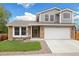 Inviting front of home with brick and siding, complemented by a lush lawn and a spacious two-car garage at 11131 Seton Pl, Westminster, CO 80031