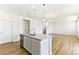 Kitchen island with granite countertop and sink, opening to living room and staircase at 9886 Ceylon Ct, Commerce City, CO 80022