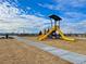 Community playground with a yellow slide, wood chip ground cover, and access path at 9886 Ceylon Ct, Commerce City, CO 80022