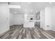 Open-concept living room with wood floors leading into a modern kitchen featuring gray cabinets and white countertops at 5688 N Killarney Ct, Aurora, CO 80019