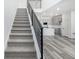 Carpeted staircase with sleek, black modern railing leading to an open-concept living space and kitchen at 5688 N Killarney Ct, Aurora, CO 80019