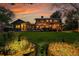 Backyard at dusk featuring exterior lighting, a lush lawn, deck, pergola, and landscaped garden at 7678 Newman St, Arvada, CO 80005
