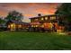 Backyard view featuring professional landscaping, a pergola-covered patio, and a large grassy area, all illuminated at twilight at 7678 Newman St, Arvada, CO 80005