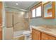 Bright bathroom featuring a shower with glass doors, a vanity, a toilet, and a large window for natural light at 7678 Newman St, Arvada, CO 80005