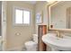 Cozy powder room featuring a pedestal sink, decorative mirror, and natural light at 7678 Newman St, Arvada, CO 80005