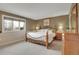 Spacious bedroom with a large window, an ornate bed frame, and hardwood dressers with vintage lamps and decor at 7678 Newman St, Arvada, CO 80005