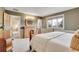 Bright bedroom featuring a plush white bed, neutral walls, and a wooden dresser with a stylish accent mirror at 7678 Newman St, Arvada, CO 80005
