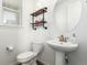 Cozy half bathroom with modern fixtures, pedestal sink, and stylish wood shelving at 17470 E 95Th Pl, Commerce City, CO 80022