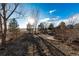 Landscaped backyard featuring trees casting shadows on the ground, a wooden fence, and a patio area at 1120 Antelope W Dr, Bennett, CO 80102