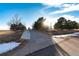 Long concrete driveway leading to a house with mature trees and landscaping at 1120 Antelope W Dr, Bennett, CO 80102