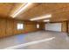 Spacious garage with wood paneling, concrete floor, and an automatic door at 1120 Antelope W Dr, Bennett, CO 80102