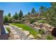 Landscaped backyard with stone steps, lush greenery, rock garden and terraced planting beds at 24322 E Mineral Dr, Aurora, CO 80016