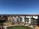 An exterior view shows contemporary townhomes in a community with a playground, clear blue sky and mountain views at 2879 W Parkside Pl, Denver, CO 80221