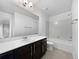 Well-lit bathroom featuring a white vanity, large mirror, and tiled shower-tub combination at 8236 E 137Th Dr, Thornton, CO 80602