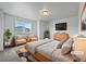 Bright bedroom featuring a large bed, sitting area by the window, and a mounted TV at 8236 E 137Th Dr, Thornton, CO 80602