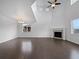 A spacious living room featuring dark wood floors, a fireplace, and soaring vaulted ceilings at 8236 E 137Th Dr, Thornton, CO 80602