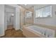 Bright bathroom featuring a glass-enclosed shower, a soaking tub, and neutral tile at 16043 Bridle Ridge Dr, Monument, CO 80132