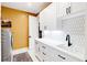 Bright laundry room with white cabinets, hexagon tile, and modern sink at 6816 Goldbranch Dr, Niwot, CO 80503