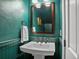 Charming powder room boasts green walls and a pedestal sink with bronze fixtures at 1423 Elizabeth St, Denver, CO 80206