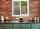 Kitchen with green cabinets and brick wall, black countertop, and a window overlooking greenery at 1423 Elizabeth St, Denver, CO 80206