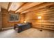 Cozy bedroom with wood beam ceiling, log walls, and large window overlooking the forest at 17940 Smugglers Rd, Monument, CO 80132