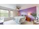 Cozy bedroom with a large window, a bed, a ceiling fan, and a decorative purple accent wall at 10517 Clermont Way, Thornton, CO 80233