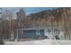 Blue home with a flat roof and stairs leading to a porch, all surrounded by trees at 629 Copperdale Ln, Golden, CO 80401