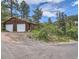 Rustic two-car garage set among mature trees; features a dirt drive and ample outdoor storage at 629 Copperdale Ln, Golden, CO 80401