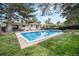 Large backyard with lush green grass, a pool, mature trees and outdoor seating area at 10473 W Arkansas Dr, Lakewood, CO 80232
